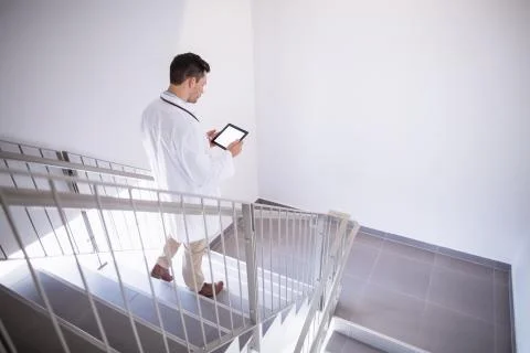 Doctor using digital tablet while walking down staircase Foto stock