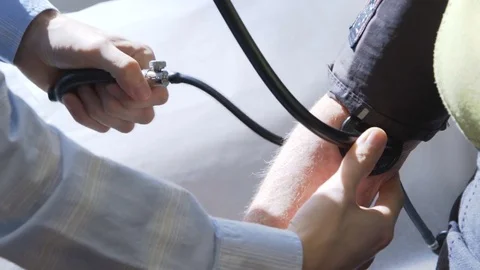Doctor using inflatable cuff to check blood pressure of patient Stock Footage 85370595
