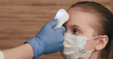 Doctor using infrared thermometer checking body temperature of a girl Stock Footage 133705813