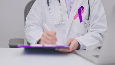 Doctor using laptop and report notes on notebook. purple and pink ribbon co.. Stock Footage 341379975