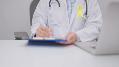 Doctor using laptop and report notes on notebook for Gold Yellow Ribbon for.. Stock Footage 341383763