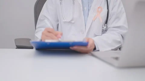 Doctor using laptop and report notes on notebook. peach ribbon concept of S.. Stock Footage 341383843