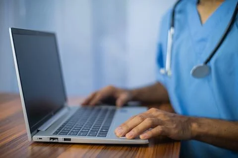 Doctor using laptop computer on desk office Stock Photos