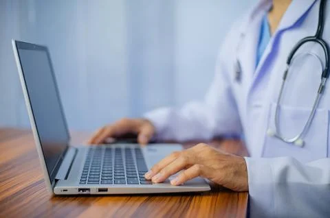 Doctor using laptop computer on desk office Stock Photos