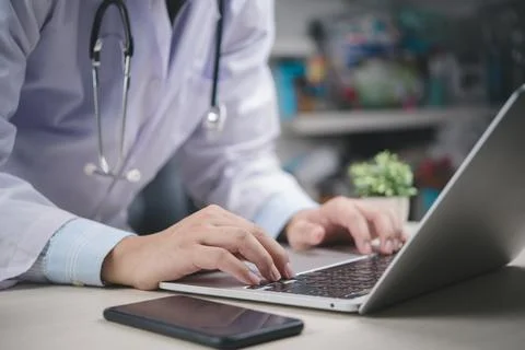 Doctor using laptop computer in office, working on medical records, digital.. Stock Photos
