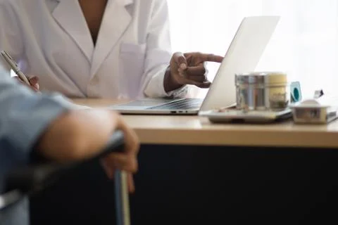Doctor Using Laptop On Table By Disabled Woman Stock Photos