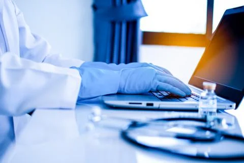Doctor using a laptop for typing data, description into a server computer i.. Stock Photos