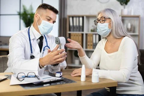 Doctor using modern thermometer for examining aged woman Stock Photos