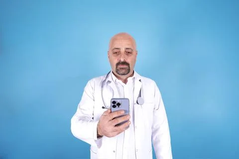 Doctor using smartphone, typing, browsing over blue background. Copy space. Foto stock
