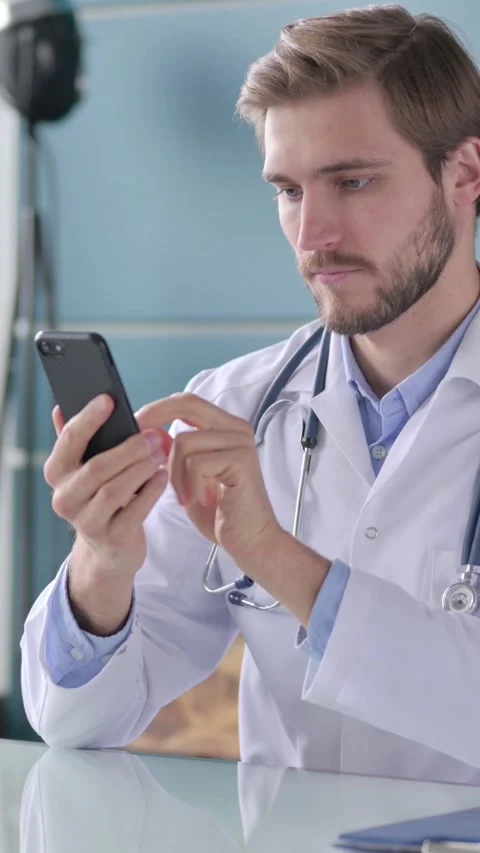 Doctor using Smartphone While Sitting in Office, Vertical Video Stock Footage 339580287