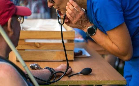 Doctor using sphygmomanometer with stethoscope checking blood pressure to a.. Stock Photos
