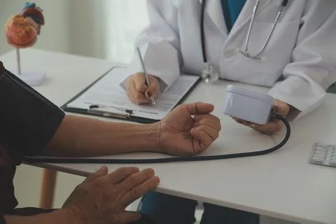 Doctor using sphygmomanometer with stethoscope checking blood pressure to a.. Fotos de archivo
