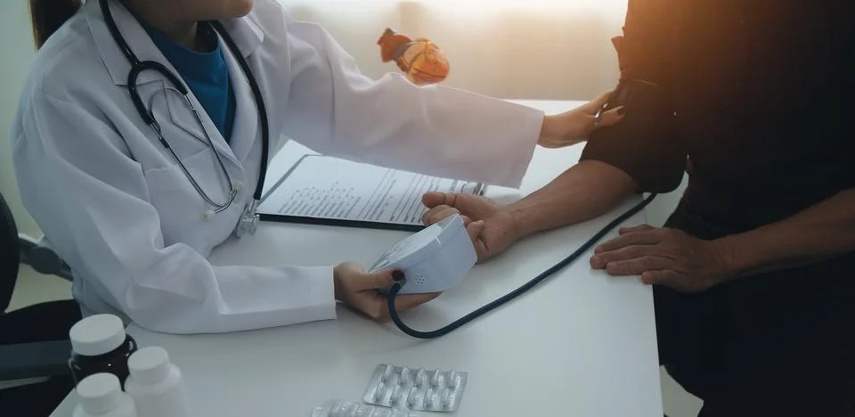 Doctor using sphygmomanometer with stethoscope checking blood pressure to a.. Foto stock