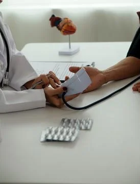 Doctor using sphygmomanometer with stethoscope checking blood pressure to a.. 写真素材