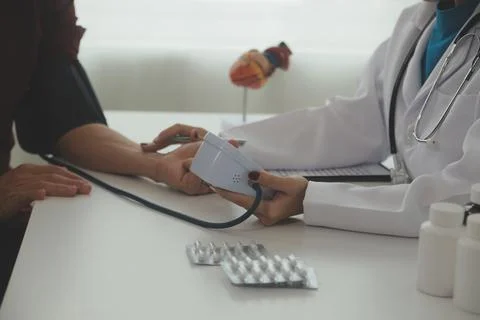 Doctor using sphygmomanometer with stethoscope checking blood pressure to a.. Fotos de archivo