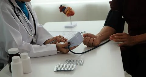 Doctor using sphygmomanometer with stethoscope checking blood pressure to a.. 写真素材