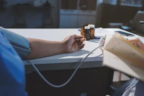 Doctor using sphygmomanometer with stethoscope checking blood pressure to a.. Fotos de archivo