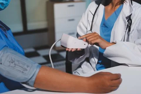 Doctor using sphygmomanometer with stethoscope checking blood pressure to a.. Stock Photos