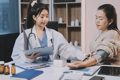 Doctor using sphygmomanometer with stethoscope checking blood pressure to a.. 写真素材