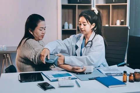 Doctor using sphygmomanometer with stethoscope checking blood pressure to a.. Stock Photos