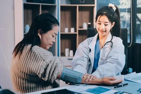 Doctor using sphygmomanometer with stethoscope checking blood pressure to a.. 写真素材
