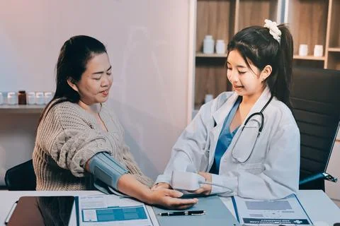Doctor using sphygmomanometer with stethoscope checking blood pressure to a.. Stock Photos