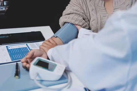 Doctor using sphygmomanometer with stethoscope checking blood pressure to a.. Stock Photos