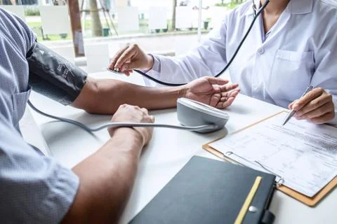 Doctor using stethoscope checking measuring arterial blood pressure on arm to Stock Photos