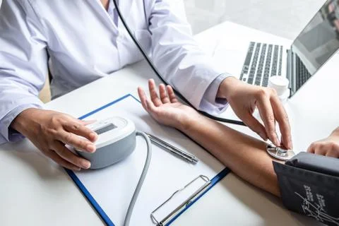 Doctor using stethoscope checking measuring arterial blood pressure on arm to Stock Photos