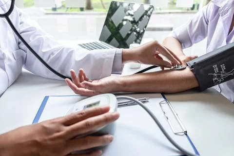 Doctor using stethoscope checking measuring arterial blood pressure on arm to Stock Photos
