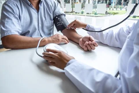 Doctor using stethoscope checking measuring arterial blood pressure on arm to Stock Photos