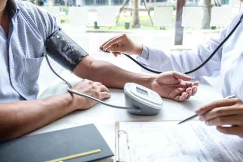 Doctor using stethoscope checking measuring arterial blood pressure on arm to Stock Photos