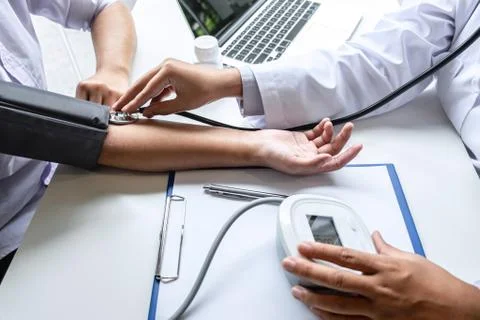 Doctor using stethoscope checking measuring arterial blood pressure on arm to Stock Photos