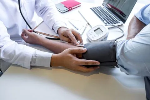 Doctor using stethoscope checking measuring arterial blood pressure on arm to Stock Photos