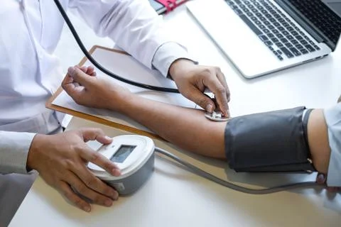 Doctor using stethoscope checking measuring arterial blood pressure on arm to Stock Photos