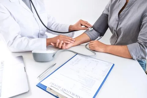 Doctor using stethoscope checking measuring arterial blood pressure on arm to Stock Photos