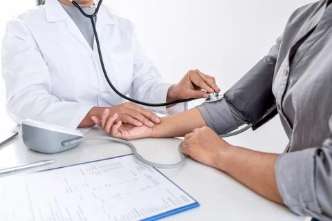 Doctor using stethoscope checking measuring arterial blood pressure on arm to Stock Photos