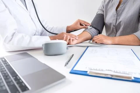 Doctor using stethoscope checking measuring arterial blood pressure on arm to Stock Photos