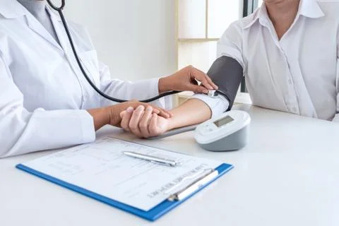 Doctor using stethoscope checking measuring arterial blood pressure on arm to Stock Photos