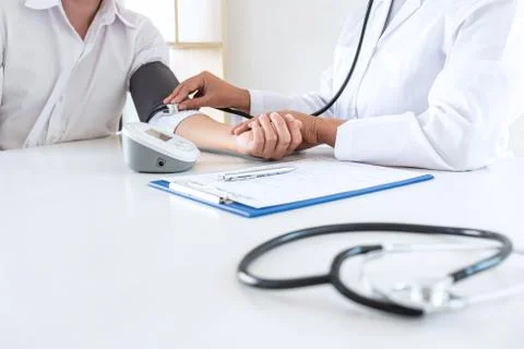 Doctor using stethoscope checking measuring arterial blood pressure on arm to Stock Photos