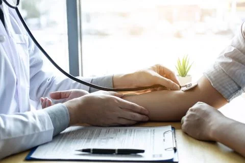 Doctor using a stethoscope checking patient with examining, presenting result Stock Photos