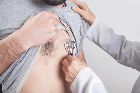 Doctor using a stethoscope checking patient heart. Stock Photos
