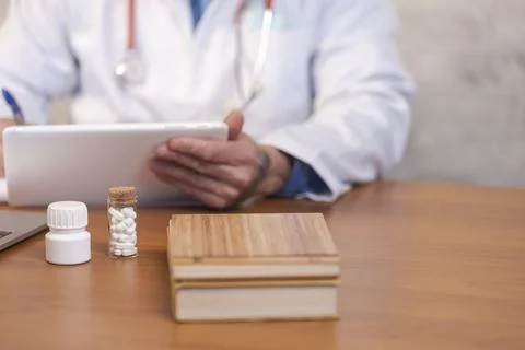 Doctor using tablet with medication on desk Stock Photos