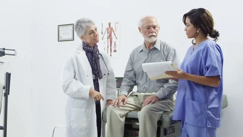 Doctor using tablet with nurse talking to elderly patient Stock Footage 80131191
