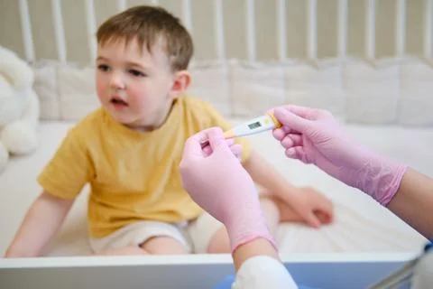 The doctor is using an thermometer to take the temperature of the child. Ki.. Stock Photos