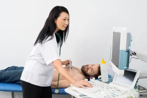 Doctor Using Ultrasound Machine While Examining Patient Stock Photos