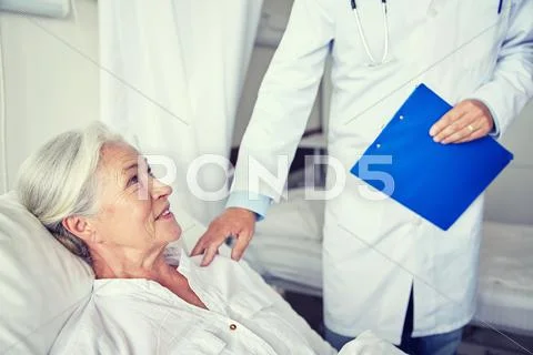 Doctor visiting happy senior woman at hospital Stock Photos