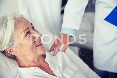 Doctor visiting happy senior woman at hospital Stock Photos