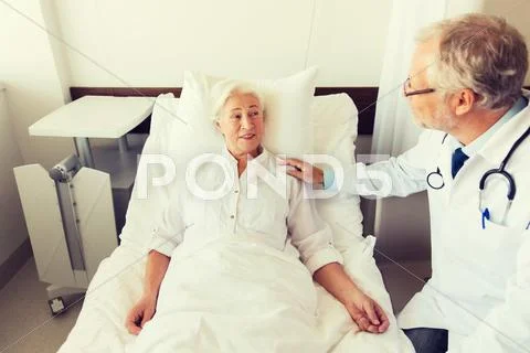 Doctor visiting senior woman at hospital ward Stock Photos