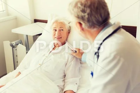 Doctor visiting senior woman at hospital ward Stock Photos
